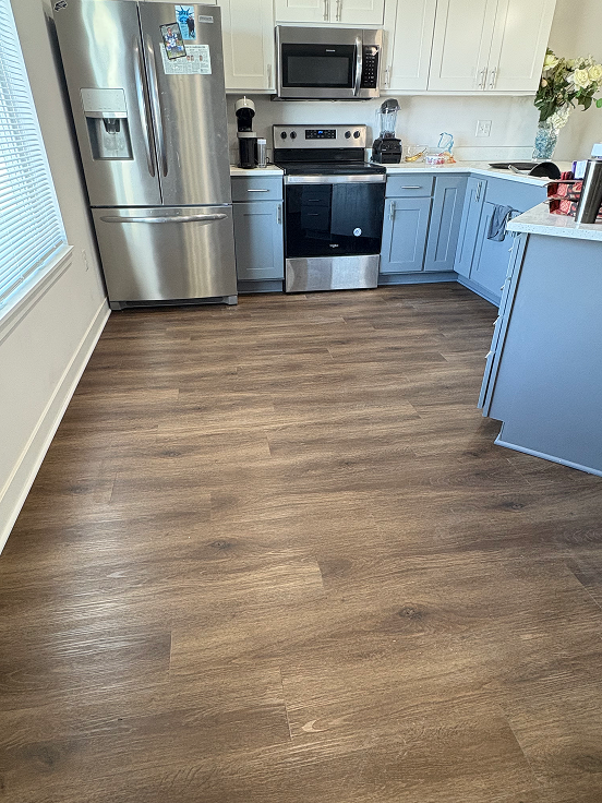 A wood-look kitchen floor installed by Bisbee's Flooring Center in the McFarland area. Gray cabinets and a warm plank keep the room calm.