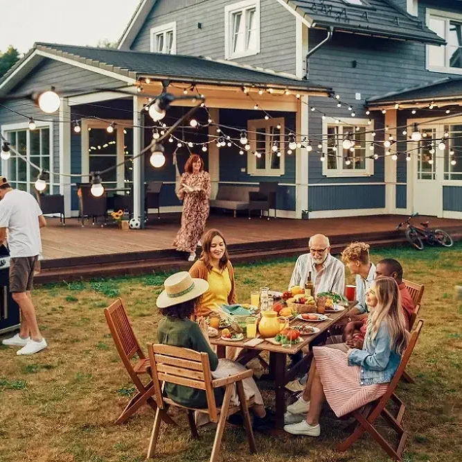 Family gathered around summer BBQ with wooden furniture